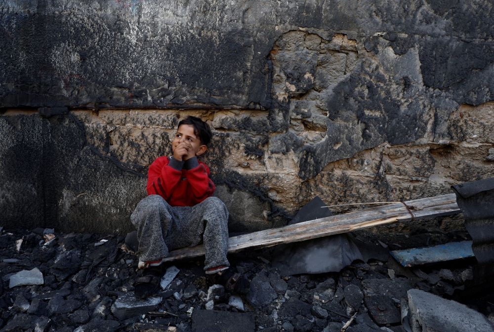 A Palestinian child sits near the site of Israeli strikes on houses after a temporary truce between Palestinian Islamist group Hamas and Israel expired, in Khan Younis in the southern Gaza Strip, December 1, 2023. — Reuters pic