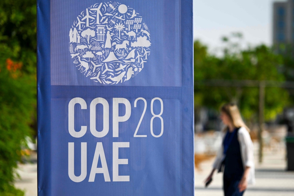 A woman walks past a COP28 logo ahead of the United Nations climate summit in Dubai November 28, 2023. — AFP pic