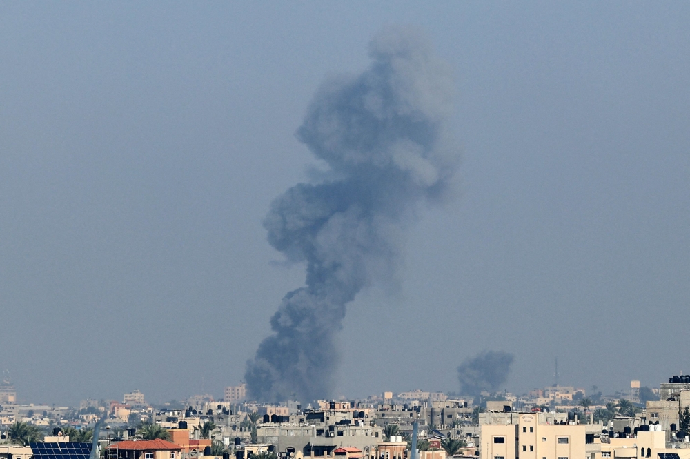 Smoke rises above buildings during Israeli strikes on Khan Yunis in the southern Gaza Strip, after battles resumed between Israel and Hamas December 2, 2023. — AFP pic
