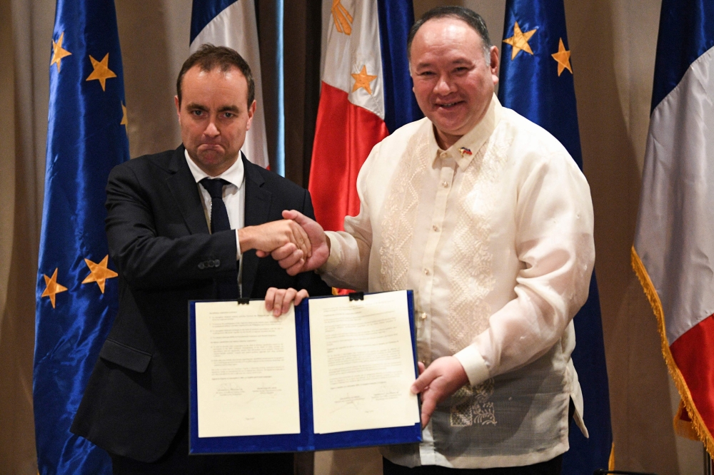France's Minister for the Armed Forces Sebastien Lecornu (left) shakes hands with Secretary of National Defense of Philippines Gilbert Teodoro after signing documents at a hotel in Manila December 2, 2023. — Ted Aljibe/Pool/AFP pic 