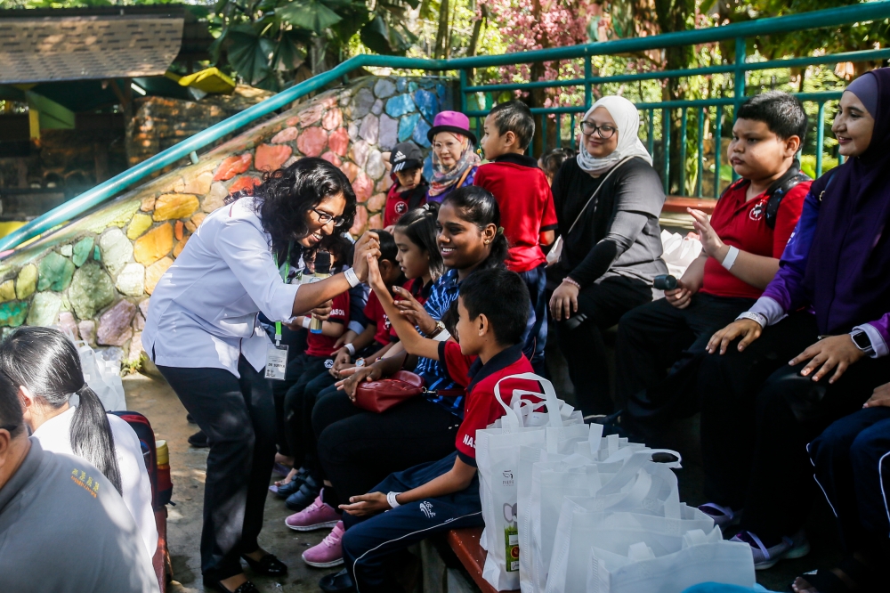 Universiti Putra Malaysia’s Institute of Tropical Agriculture and Food Security senior research officer Suriya Kumari interacts with children during the animal-assisted therapy exposure for autistic children event at Zoo Negara November 27, 2023. — Picture by Hari Anggara