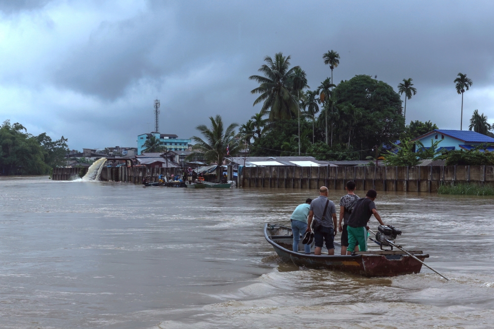 Sungai Golok residents are seen on a boat during rising water levels at the river December 2, 2023. — Bernama pic
