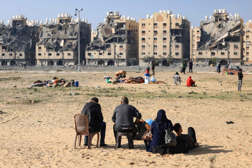 Residents of the Qatari-funded Hamad Town residential complex in Khan Yunis in the southern Gaza Strip, sit with some of their belongings as they flee their homes after an Israeli strike. — AFP pic