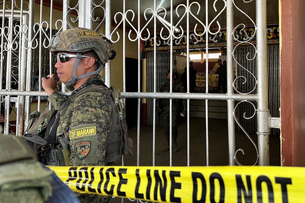 Military personnel stand guard at the entrance of a gymnasium while police investigators look for evidence after a bomb attack at Mindanao State University in Marawi. — AFP pic
