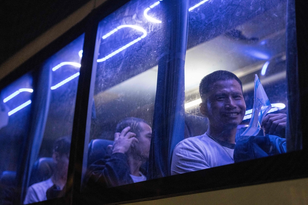 Thai nationals who were taken hostage by Hamas militants and recently released, wave from inside a bus as they leave the Shamir Medical Center near the city of Ramla, heading toward the airport to be flown home, on November 29, 2023. — AFP pic