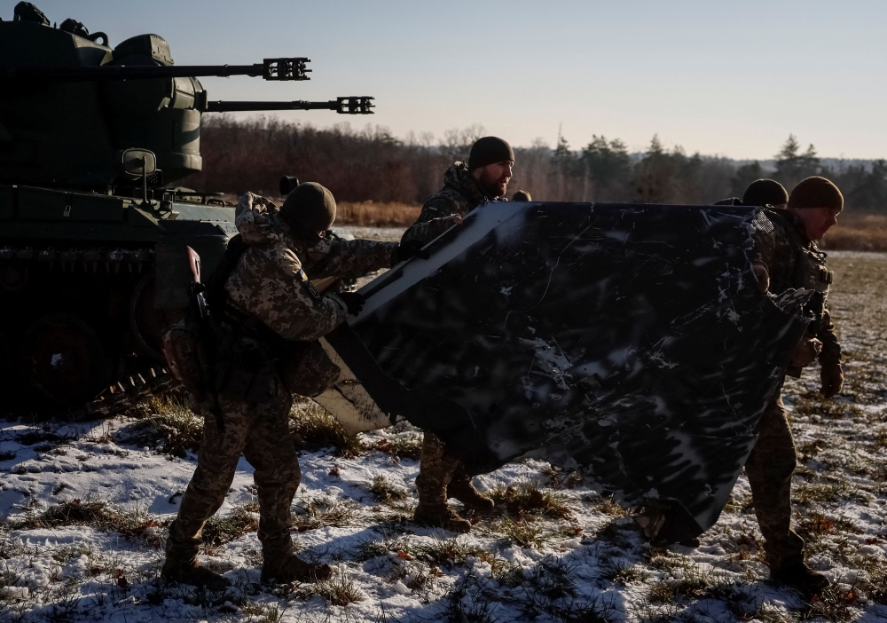 Ukrainian servicemen from air defence unit carry a part of a Russian suicide drone downed a few days ago, at their position, amid Russia's attack on Ukraine November 30, 2023. — Reuters pic