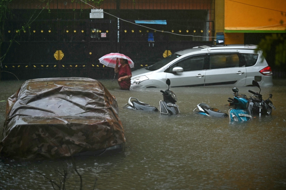 A resident wades through a flooded street after heavy rains in Chennai on December 4, 2023. Cyclone Michuang is expected to make landfall on December 5 along the southern coast. — AFP pic