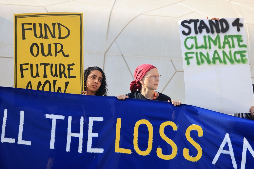 Activists lift placards and chant slogans calling on the world's biggest CO2 emitters to fill the 'Loss and Damage' fund supporting the adaptation and development of countries most vulnerable to climate change, at the COP28 United Nations climate summit in Dubai on December 4, 2023. — AFP pic
