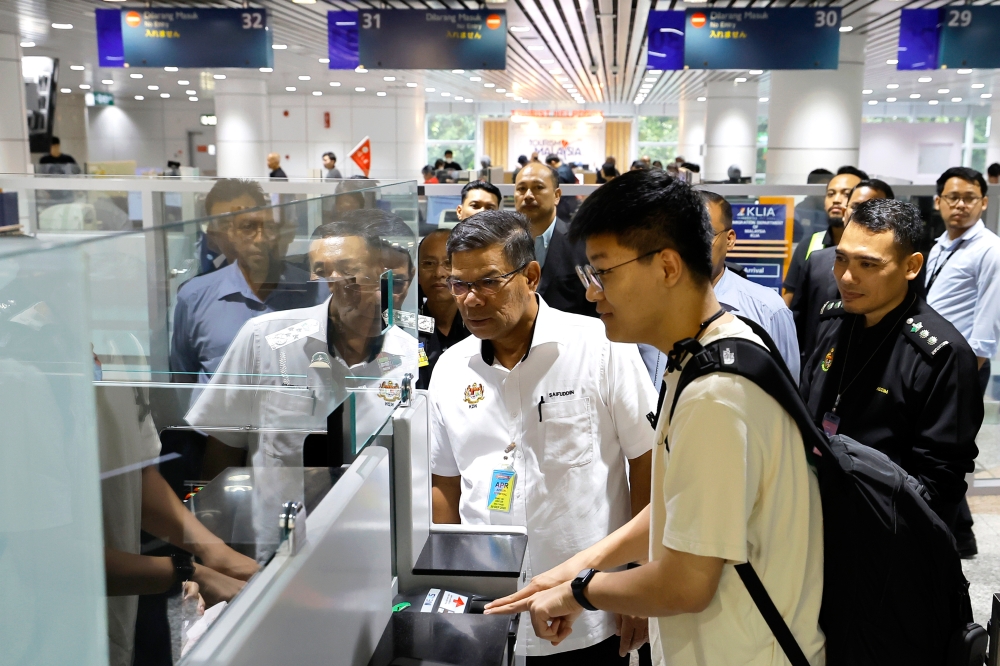 Home Minister Datuk Seri Saifuddin Nasution Ismail watches an incoming tourist at the passport counter during an inspection of the implementation of the Visa Liberalisation Plan at Kuala Lumpur International Airport (KLIA) Terminal 1, December 5, 2023. — Bernama pic  
