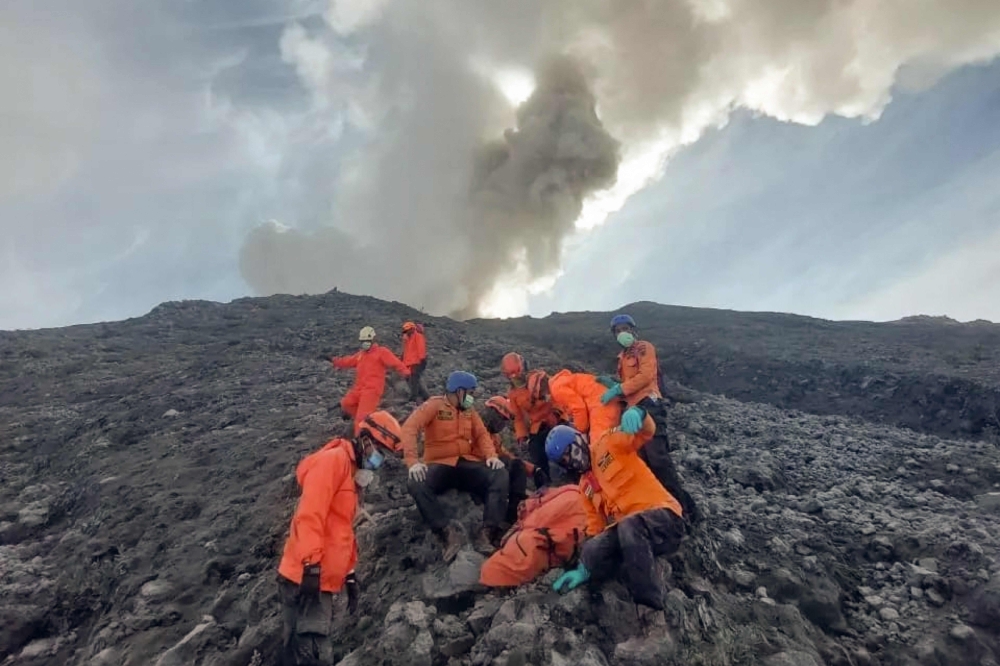 Rescuers in orange jackets and hard hats carrying a body down the side of the volcano on Tuesday. — AFP pic/National Search and Rescue Agency (Basarnas)