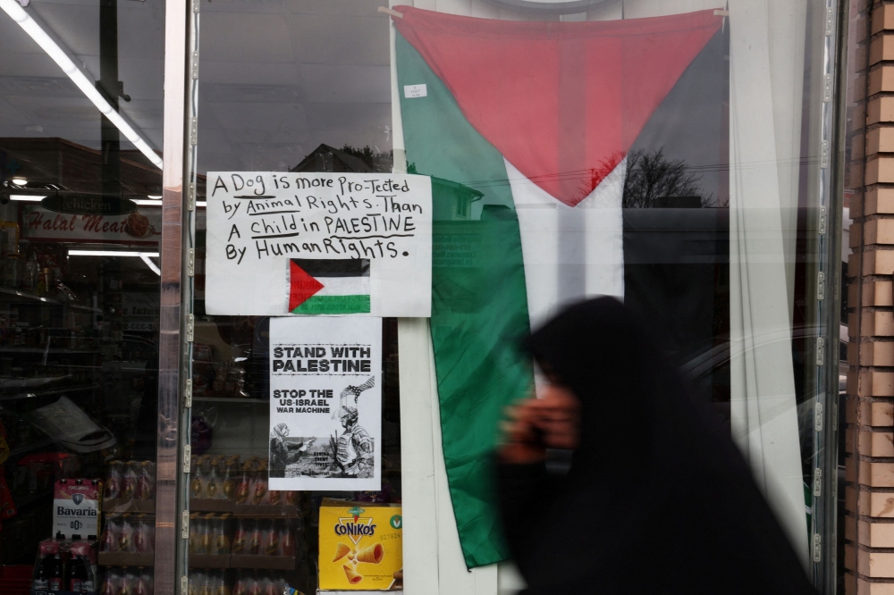 A woman walks by posters, amid the ongoing conflict between Israel and the Palestinian group Hamas, along Palestine Way in the Little Palestine neighbourhood of Paterson, New Jersey, December 5, 2023. ― Reuters pic