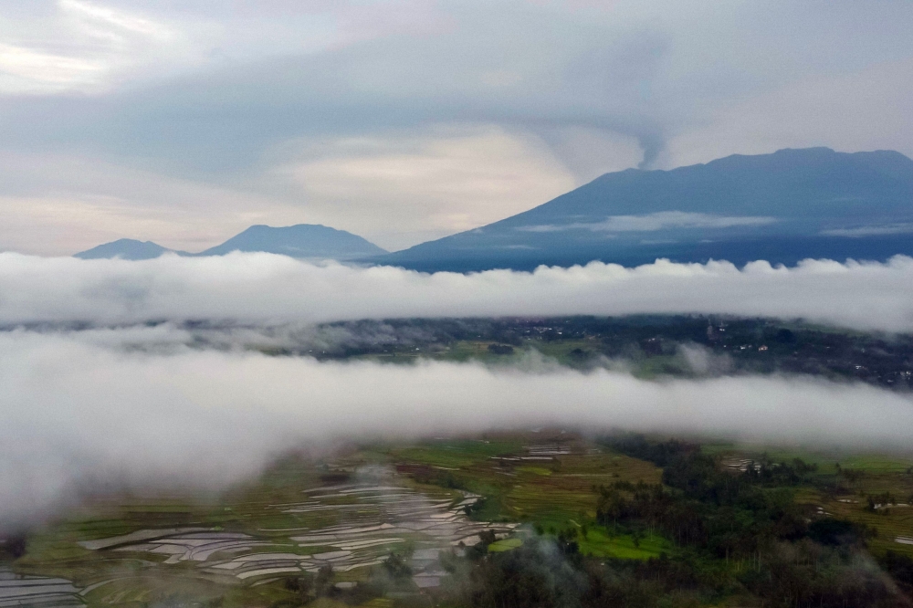 An aerial view shows Mount Marapi (background right) spewing volcanic ash during an eruption as seen from Batusangkar in Agam, West Sumatra, at dawn December 6, 2023. — AFP pic