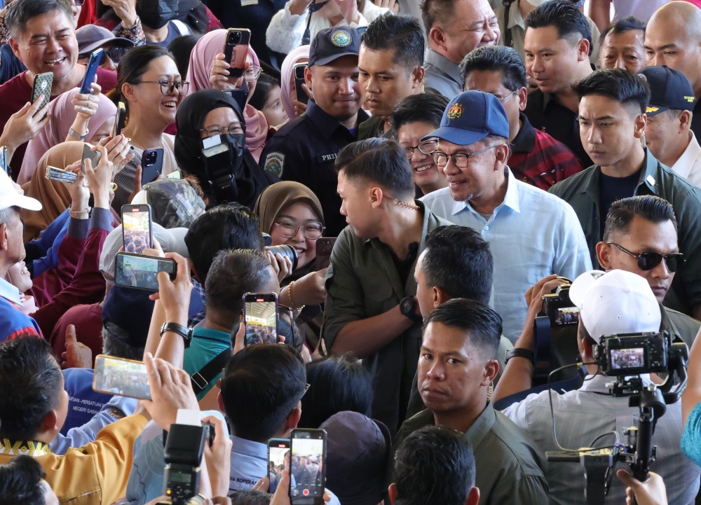 Prime Minister Datuk Seri Anwar Ibrahim greets the crowd at the opening of the National Hawkers and Petty Traders Day at Dataran Buhavan in Penampang, December 7, 2023. — Bernama pic  