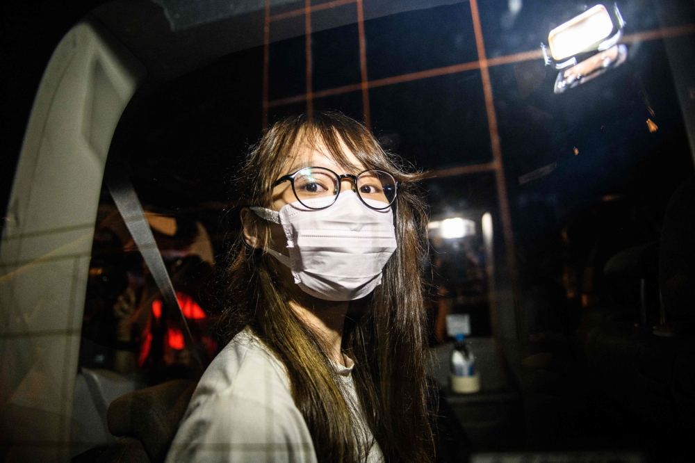 Prominent Hong Kong democracy activist Agnes Chow looks out of a car window while being driven away by police from her home after she was arrested under the new national security law in Hong Kong late on August 10, 2020. — AFP pic