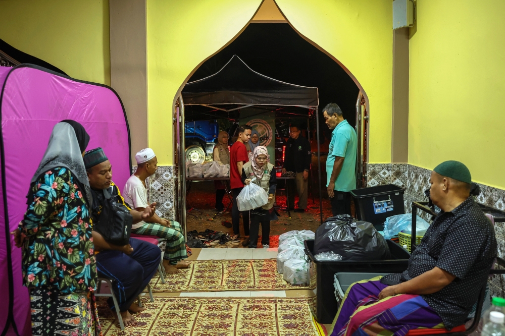 Flood evacuees at a relief centre at the Padang Licin mosque in Pasir Mas receive food packs from International Relief and Humanitarian Outreach volunteers, December 7, 2023. — Bernama pic 