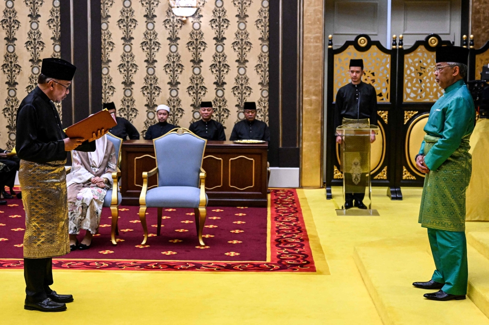 Malaysia’s King Sultan Abdullah Sultan Ahmad Shah and Malaysia’s newly appointed Prime Minister Datuk Seri Anwar Ibrahim take part in the swearing-in ceremony at the National Palace in Kuala Lumpur, November 24, 2022. — AFP pic