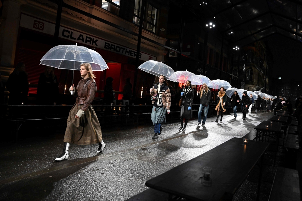 Models hold umbrellas as they rehearse prior to the 