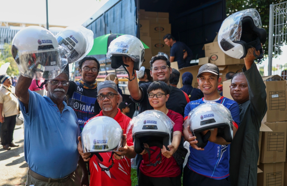 People exchange their old motorcycle helmets for new ones free of charge at the JPJ booth. — Bernama pic