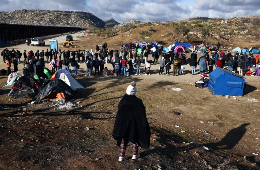 Asylum seeking migrants stand at a makeshift camp along the US-Mexico border as they await processing by the US Border Patrol on December 1, 2023 in Jacumba Hot Springs, California. — Getty Images via AFP