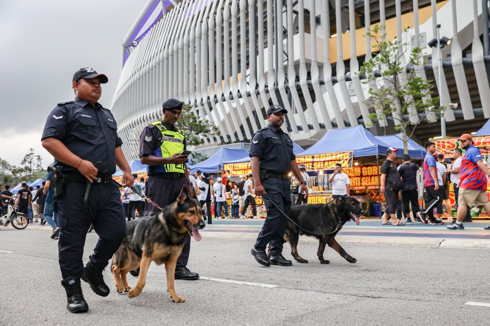 Police from the K9 unit patrol the stadium grounds. — Bernama pic