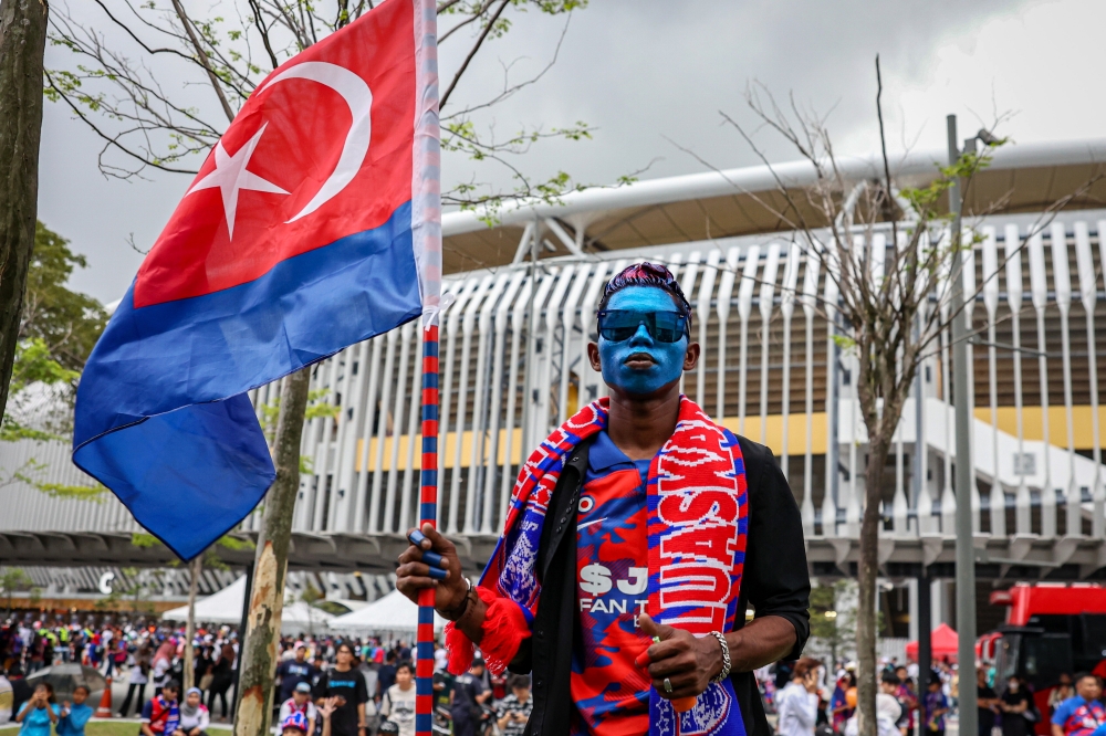 A diehard JDT fan waits outside the stadium before the gates open. — Bernama pic