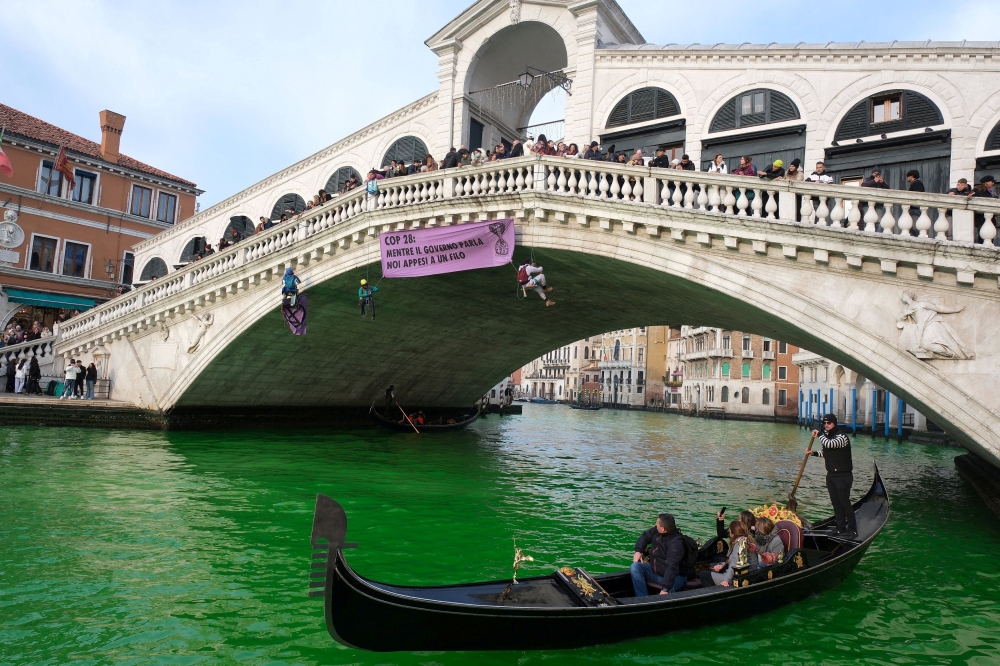 Italian environmentalists used a dye to turn Venice’s Grand Canal green yesterday in protest at what they said was a lack of progress at the COP28 climate summit in Dubai. — Reuters pic
