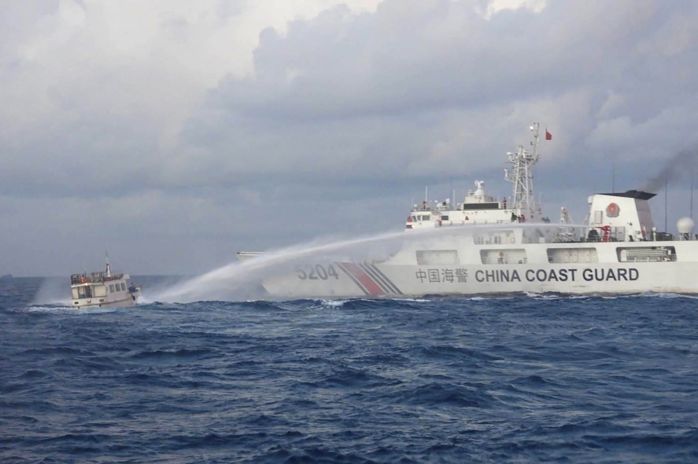 This handout photo taken and released on December 10, 2023 by the Philippine Coast Guard (PCG) shows a China Coast Guard vessel (R) using water cannon against the M/L Kalayaan chartered supply boat (L) during a mission to deliver provisions at Second Thomas Shoal in disputed waters of the South China Sea. — AFP pic/Philippine Coast Guard handout