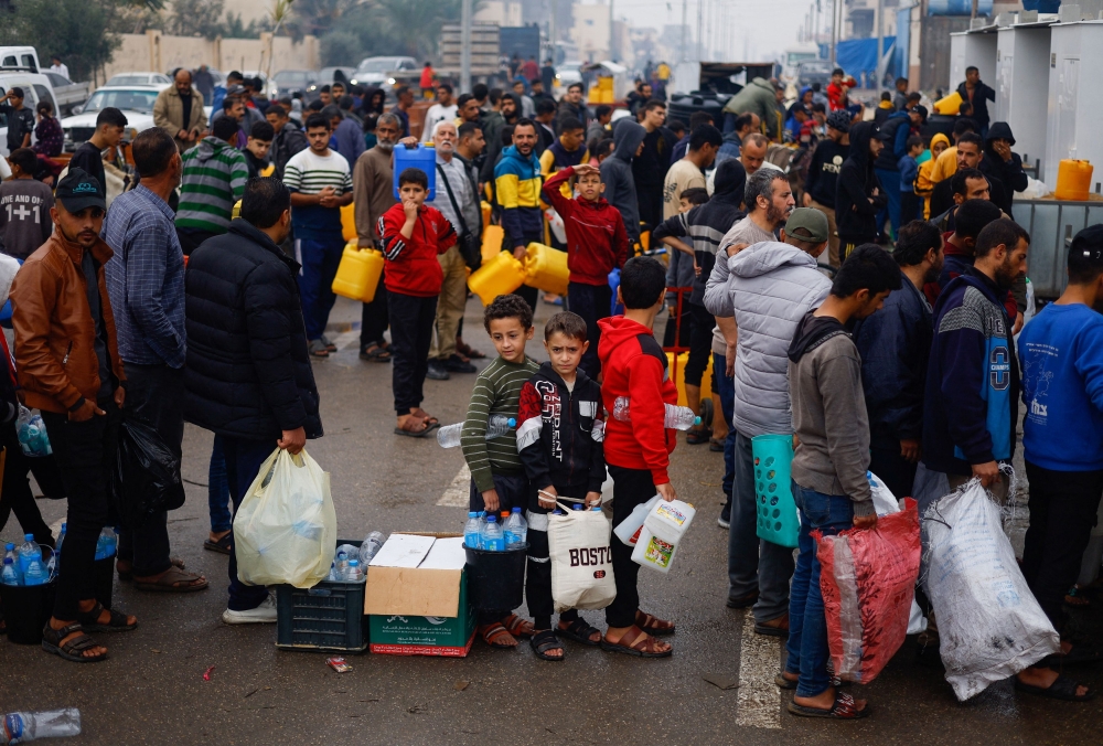 Palestinian children queue to collect water amid water shortages as Israel continues to pound Gaza. — Reuters pic