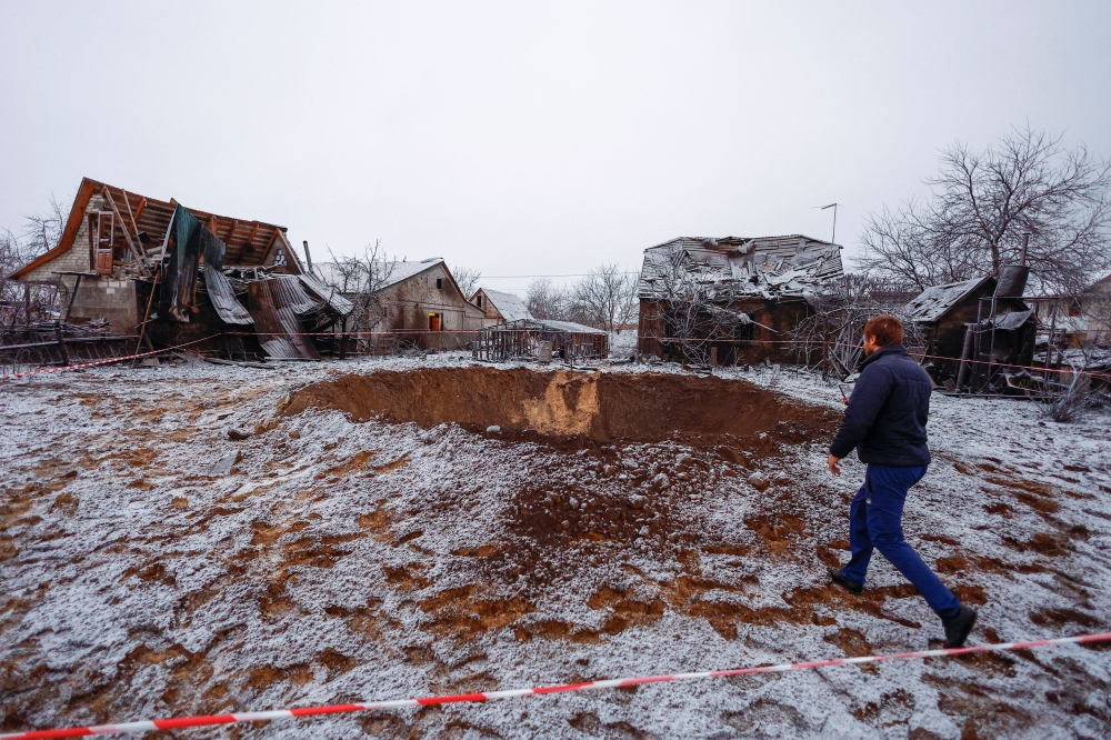 A local resident walks to a crater at a site of a Russian missile strike, amid Russia's attack on Ukraine, in Kyiv, Ukraine December 11, 2023. — Reuters pic