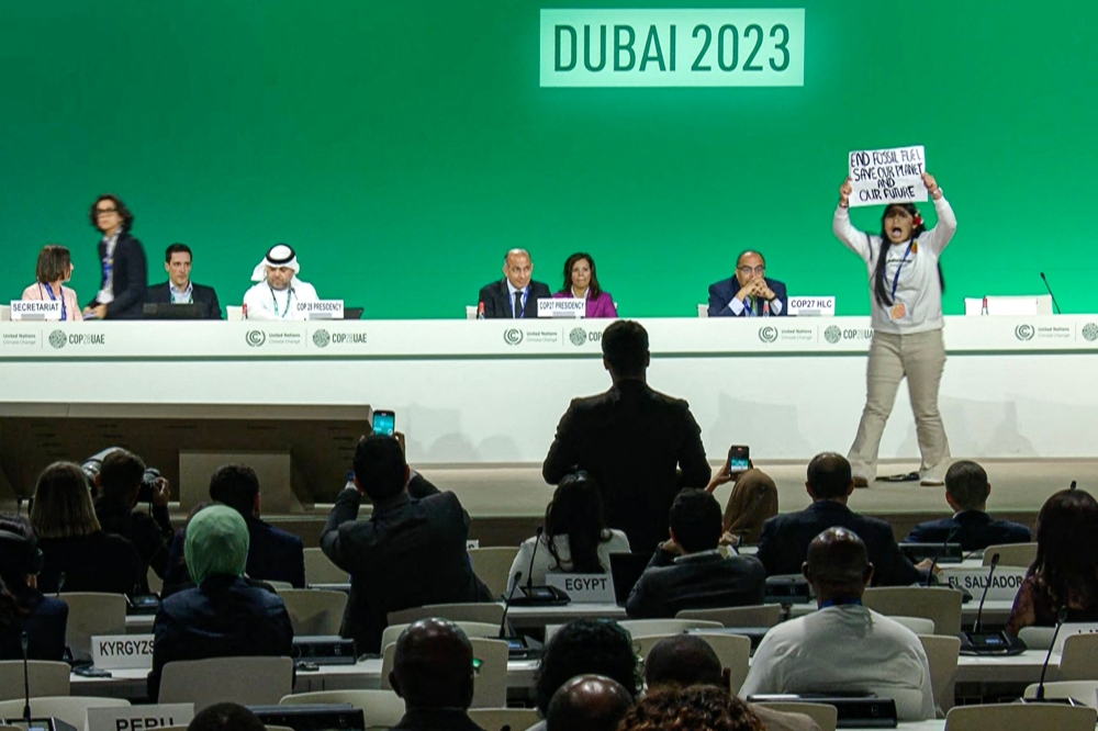 This image grab taken from AFPTV video footage shows an activist protesting on stage against fossil fuels during an event at the United Nations Climate Conference (COP28) in Dubai on December 11, 2023. — AFP pic