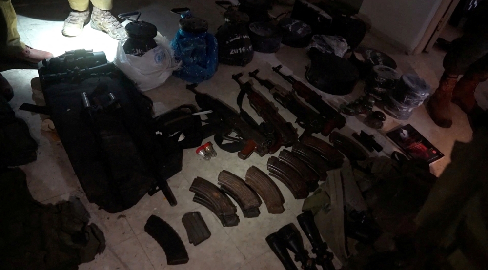 Israeli soldiers stand beside assorted weapons displayed on the floor inside a mosque in Jabalia, in the northern Gaza Strip, in this screengrab taken from video released on December 11, 2023. — Israel Defence Forces handout pic via Reuters
