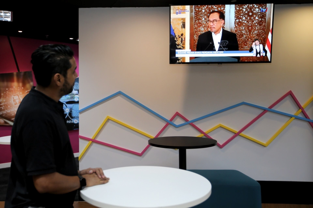 A man watches Prime Minister Datuk Seri Anwar Ibrahim’s live telecast on the new Cabinet reshuffle in a cafe near Kuala Lumpur December 12, 2023. — Picture by Ahmad Zamzahuri