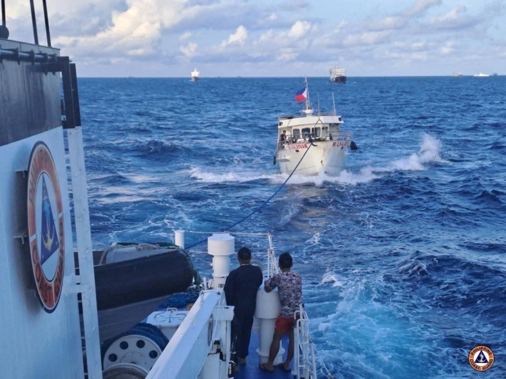 A Philippine Coast Guard ship tows a Filipino resupply vessel following damages due to water cannon from a Chinese Coast Guard ship as it was heading towards the disputed Second Thomas Shoal, in the South China Sea, December 10, 2023. — Philippine Coast Guard handout pic via Reuters