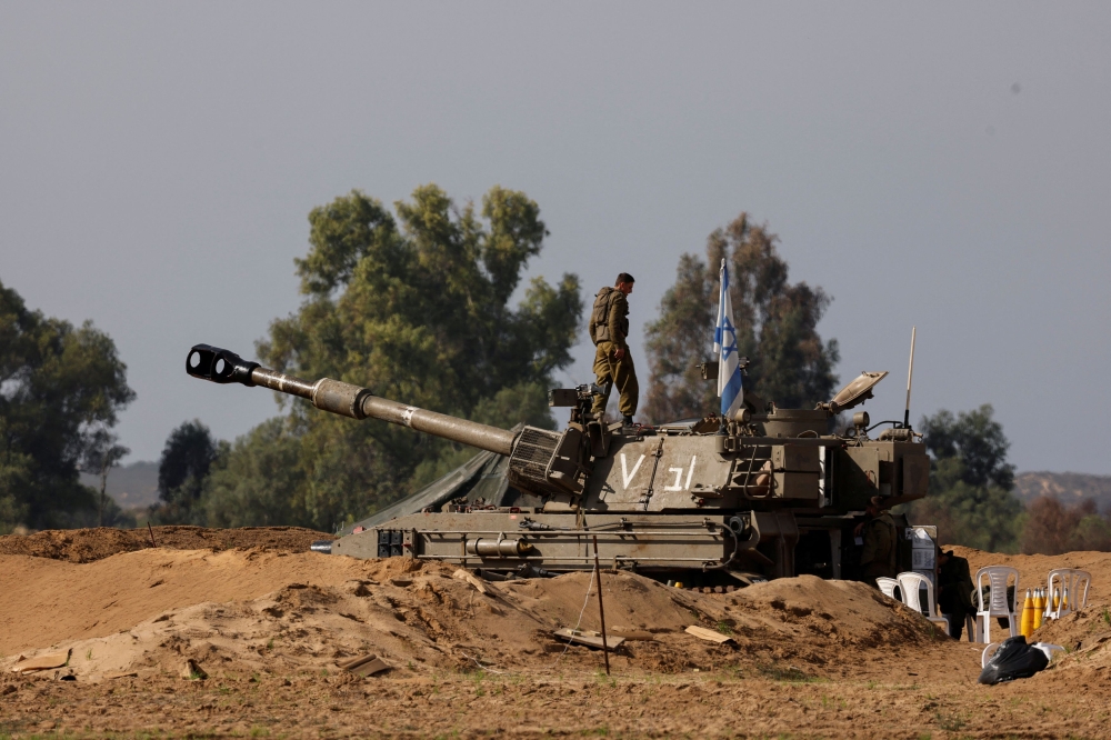 An Israeli soldier stands atop of a mobile artillery unit, amid the ongoing conflict between Israel and the Palestinian Islamist group Hamas, near the Israeli-Gaza Border, as seen from Israel December 8, 2023. — Reuters pic