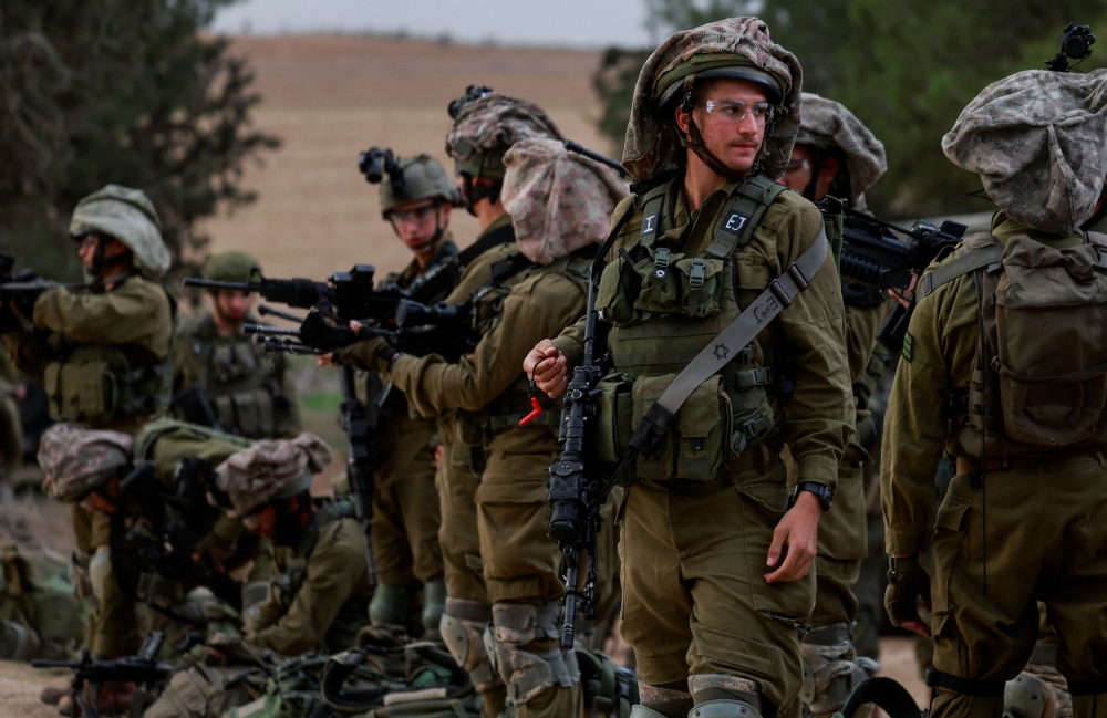 Israeli soldiers gather on the Israeli side near the border with Gaza, amid the ongoing conflict between Israel and the Palestinian Islamist group Hamas, as seen from southern Israel December 12, 2023. — Reuters pic