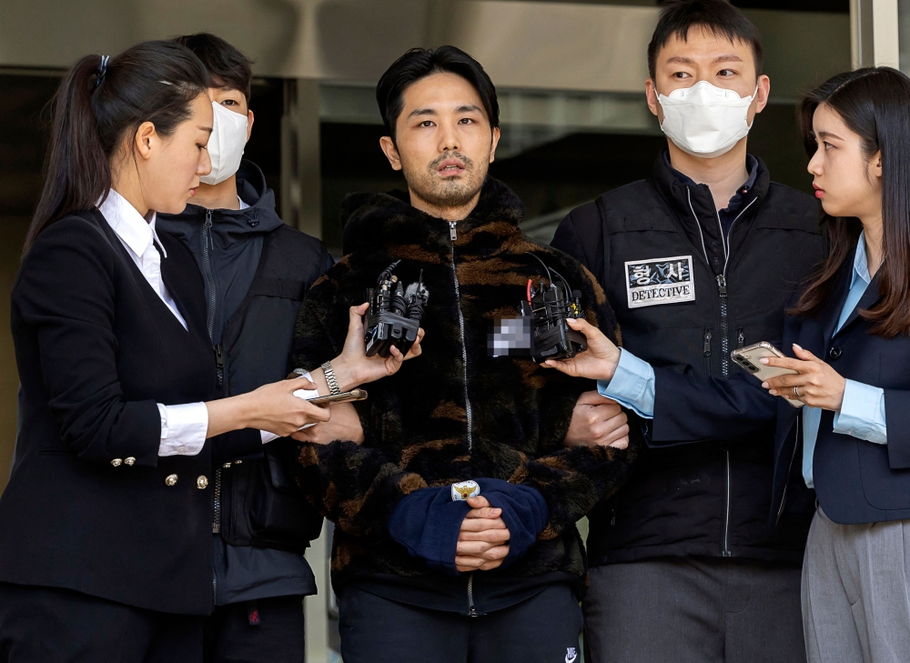This picture taken on April 9, 2023 shows South Korean Lee Kyung-woo (centre), who was arrested on charges of kidnapping and murdering a woman, being escorted by authorities as he is transferred to the prosecution from a police station in Seoul. — Picture by Yonhap via AFP 