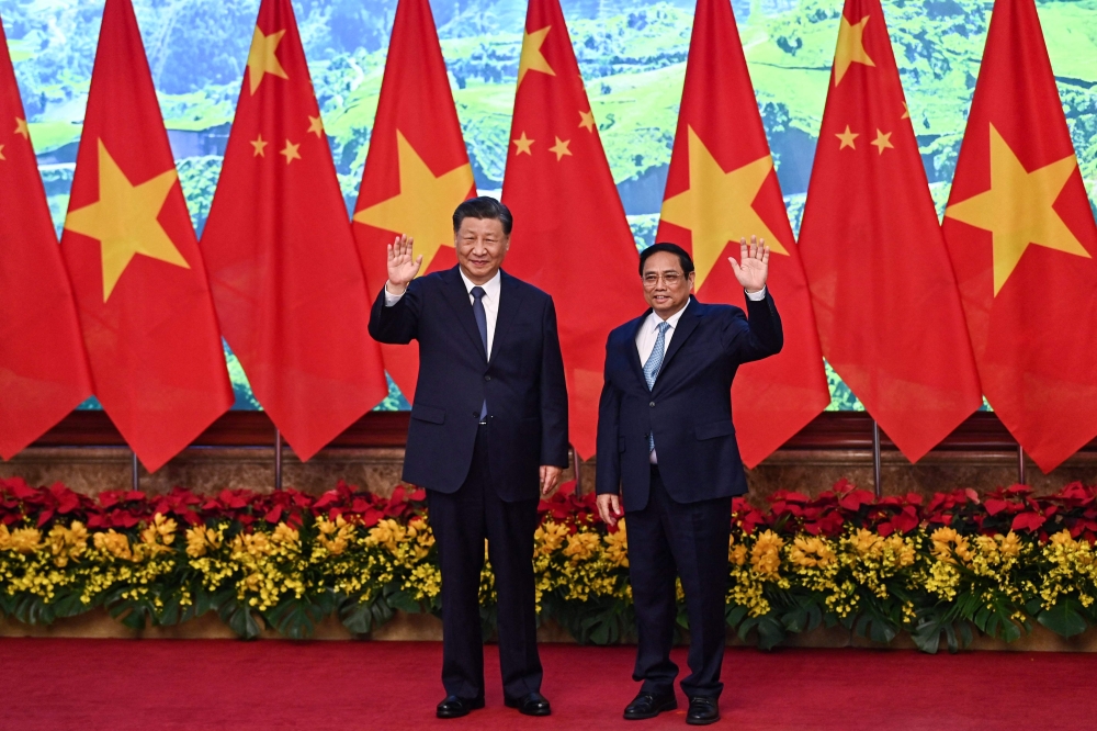Vietnam’s Prime Minister Pham Minh Chinh (right) and China’s President Xi Jinping (left) wave to the media during their meeting at the Government Office in Hanoi on December 13, 2023. China and Vietnam pledged on December 12 to deepen ties during President Xi Jinping’s first visit in six years, as Beijing seeks to counter growing US influence with the communist nation. — Nhac Nguyen/Pool/AFP pic 