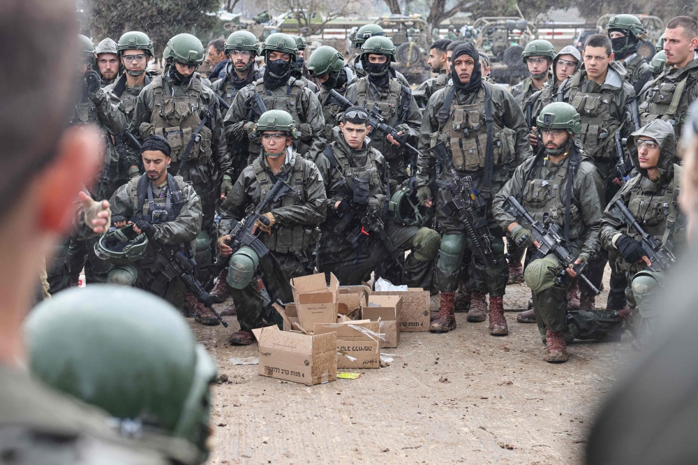 Israeli soldiers are briefed as they prepare to go to the Gaza Strip, near the border area in southern Israel on December 13, 2023 amid ongoing battles with the Palestinian Hamas movement. — AFP pic