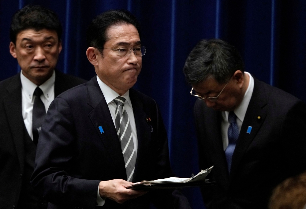 Japanese Prime Minister Fumio Kishida walks past Chief Cabinet Secretary Hirokazu Matsuno at the end of a news conference at the prime minister's office in Tokyo, Japan, 13 December 2023. — Pool pic via Reuters