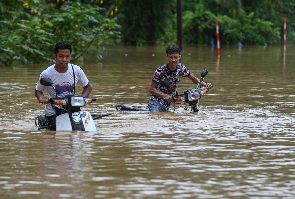 Residents traverse the flood on motorcycles in Kampung Pengkalan Ajal, Kuala Berang, Terengganu, December 14, 2023. — Bernama pic 