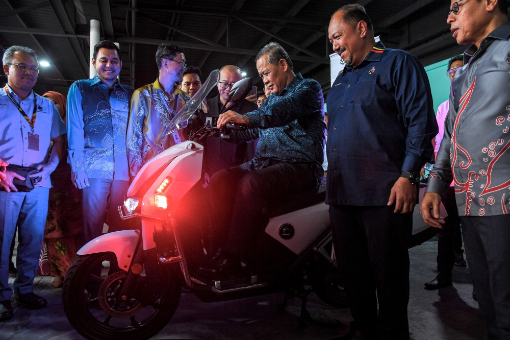Negeri Sembilan Menteri Besar Datuk Seri Aminuddin Harun (3rd right) tries riding an electric motorcycle during the launch of Careplus Mall in Seremban December 14, 2023. — Bernama pic 