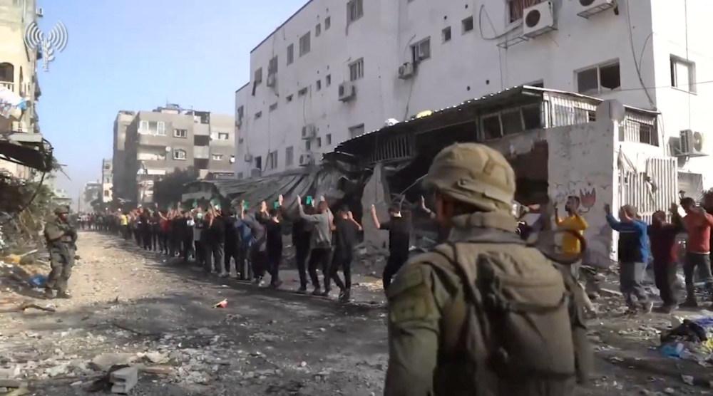 Israeli soldiers stand guard as men with raised hands are led out near Kamal Adwan hospital, amid the ongoing conflict between Israel and the Palestinian Islamist group Hamas, in Jabalia in the northern Gaza Strip, in this screen grab from a handout video released December 14, 2023. — Picture by Israel Defence Forces/Handout via Reuters