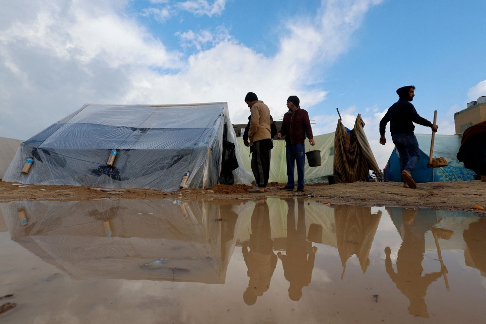 Displaced Palestinians, who fled their houses due to Israeli strikes, walk next to tents following heavy rains at tent camps, as the conflict between Israel and Hamas continues, in Rafah, in the southern Gaza Strip December 13, 2023. — Reuters pic