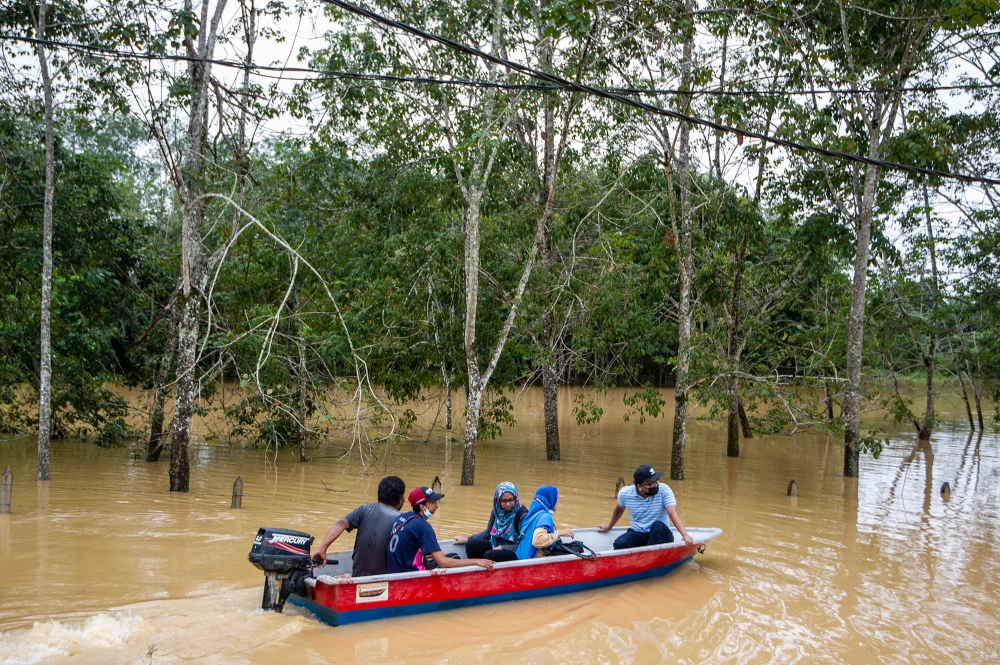 Lebak Seberang villagers ride a boat through floodwaters following a heavy monsoon downpour in Temerloh, Pahang January 9, 2021. — Picture by Shafwan Zaidon