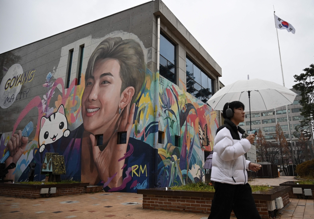 A man walks past a mural depicting RM, a member of K-pop group BTS, in Goyang, northwest of Seoul, on December 11, 2023. — AFP pic
