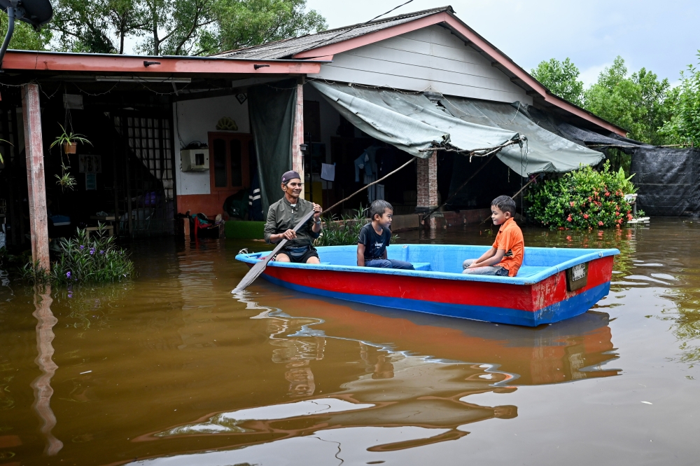 Resident Romli Abdullah (left), 60, and his grandchildren are seen in a boat during the floods in Kampung Paya, Balai Besar, Dungun December 16, 2023. — Bernama pic 