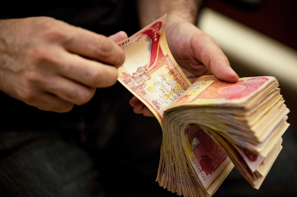 A currency exchange agent counts Iraqi Dinars at his company in Iraq's southern city of Basra, on December 12, 2023. — AFP pic