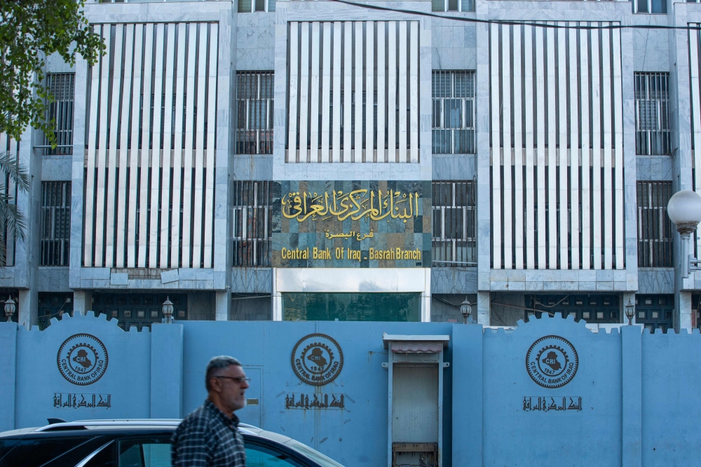 A man walks in front of the local branch of Iraq's central bank in the southern city of Basra, on December 8, 2023. — AFP pic