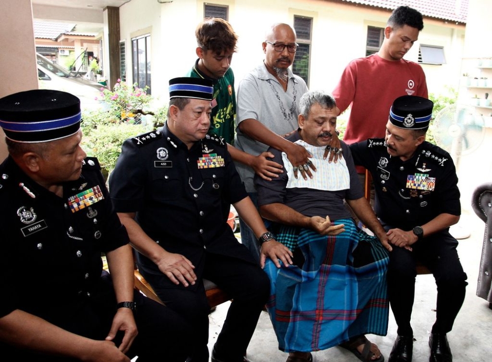 Perak Police Chief Datuk Seri Mohd Yusri Hassan Basri (seated right) comforting Muhd Zamrie Zainal Abidin, 55, father of student Mohammad Zaharif Affendi who died after being hit by a car near Sekolah Menengah Kebangsaan Jati, at his family's residence in Taman Chepor Sentosa Chemor December 16, 2023. — Bernama pic