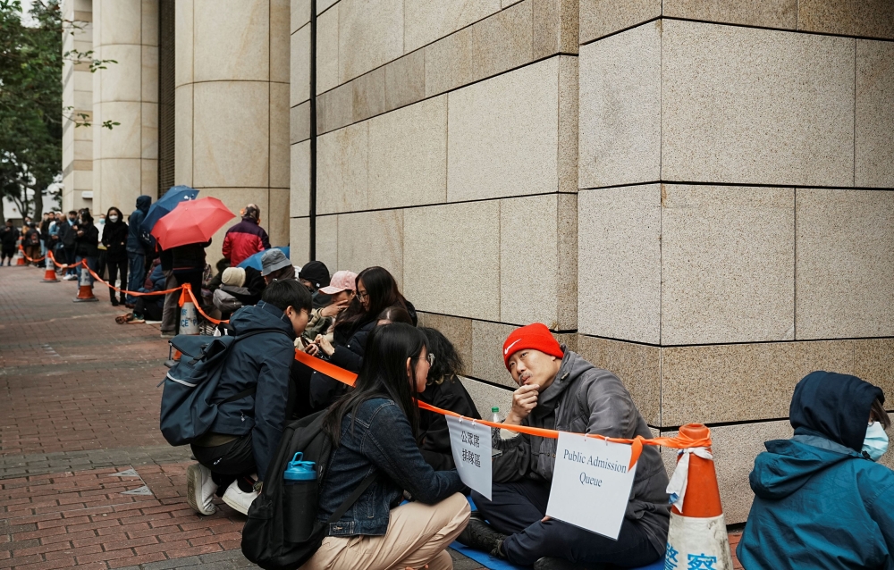 People sit while waiting in a queue outside the West Kowloon Magistrates' Courts during the national security trial of media mogul Jimmy Lai, founder of Apple Daily, in Hong Kong December 18, 2023. — Reuters pic  